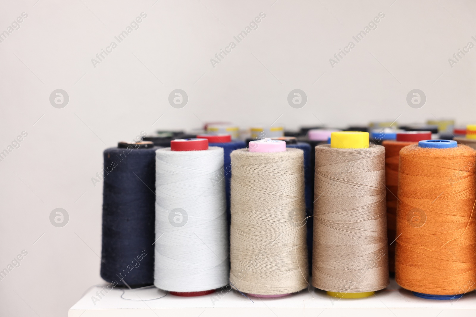 Photo of Many different spools of thread on white shelf in professional workshop