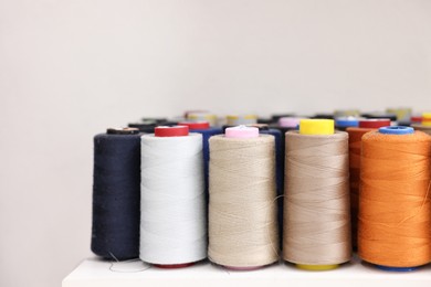 Photo of Many different spools of thread on white shelf in professional workshop