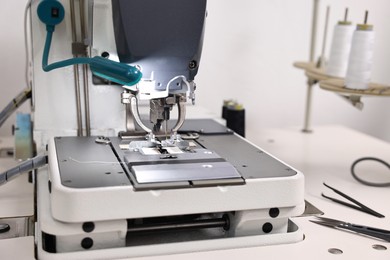 Photo of Sewing machine on white table in professional workshop, closeup