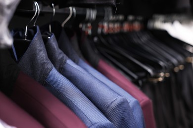 Photo of Many different clothes hanging from rack in professional workshop, closeup