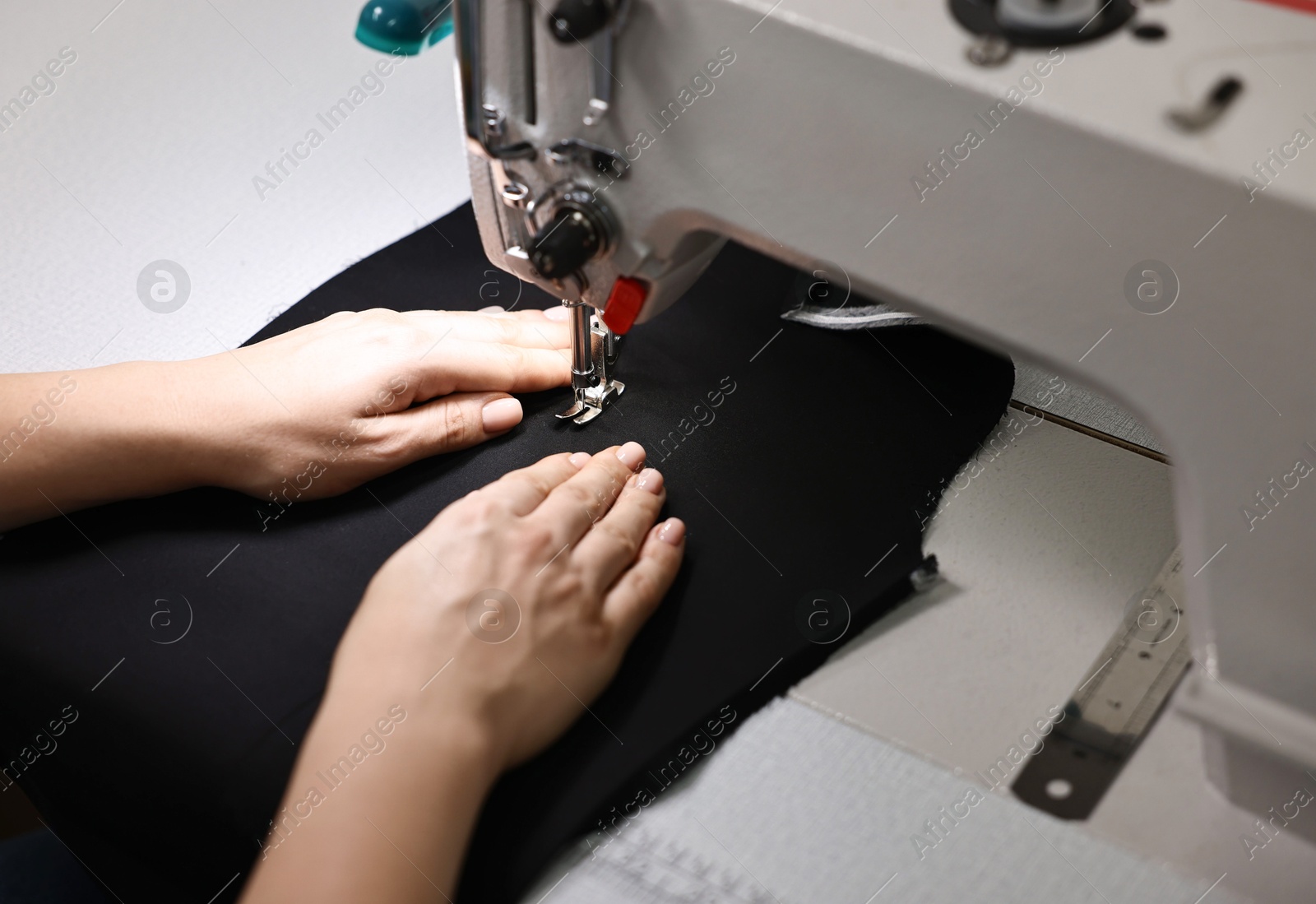 Photo of Woman working with sewing machine in professional workshop, closeup