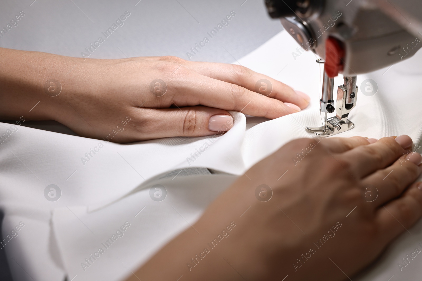 Photo of Woman working with sewing machine in professional workshop, closeup