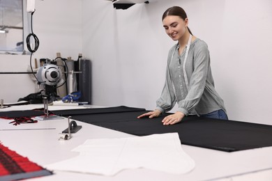 Photo of Young woman working at white table in professional workshop