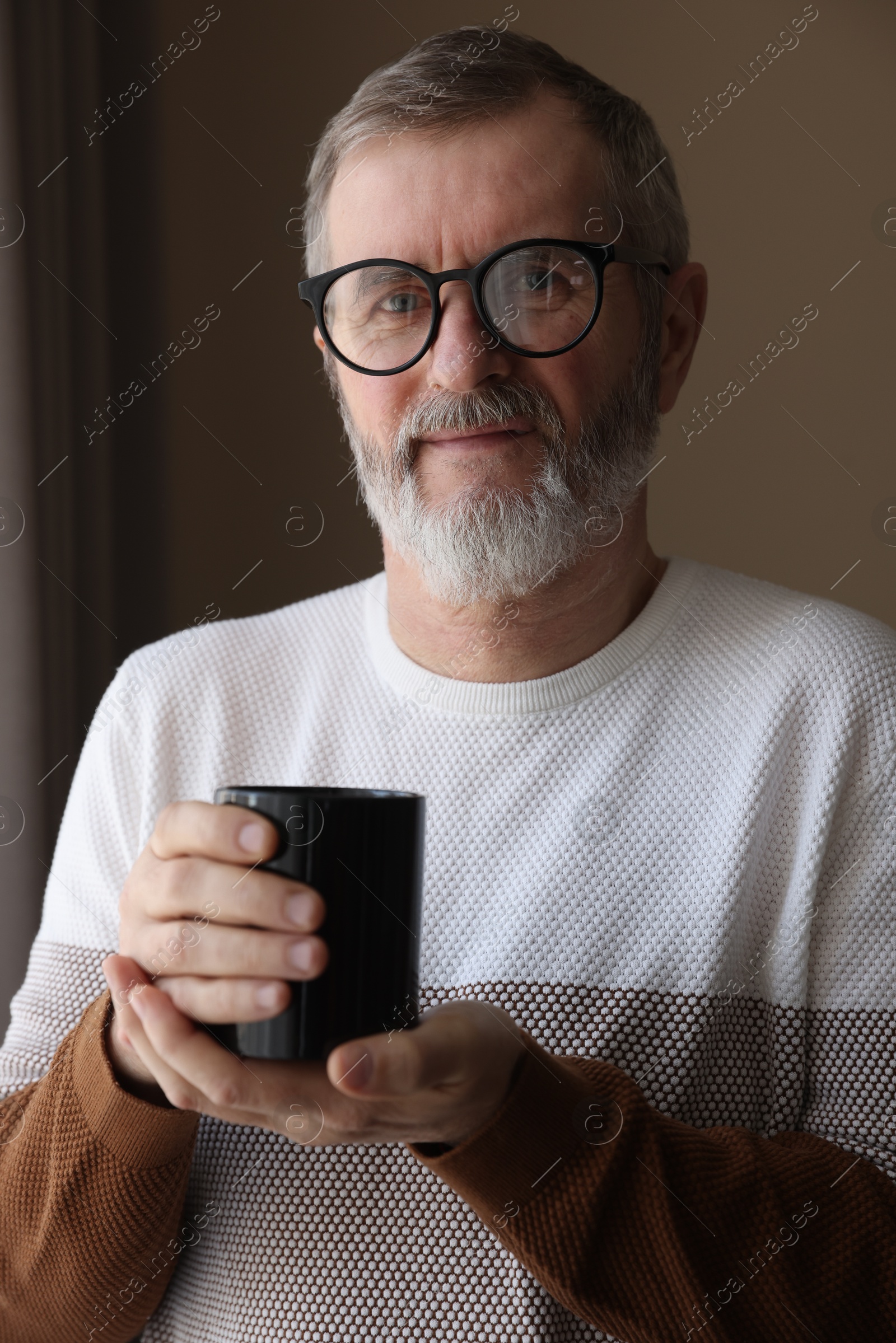 Photo of Mature man with cup of hot drink at home