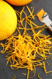 Fresh orange zest, zester and fruit on black table, flat lay