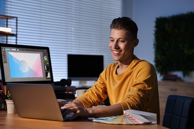 Photo of Designer working on laptop indoors at night