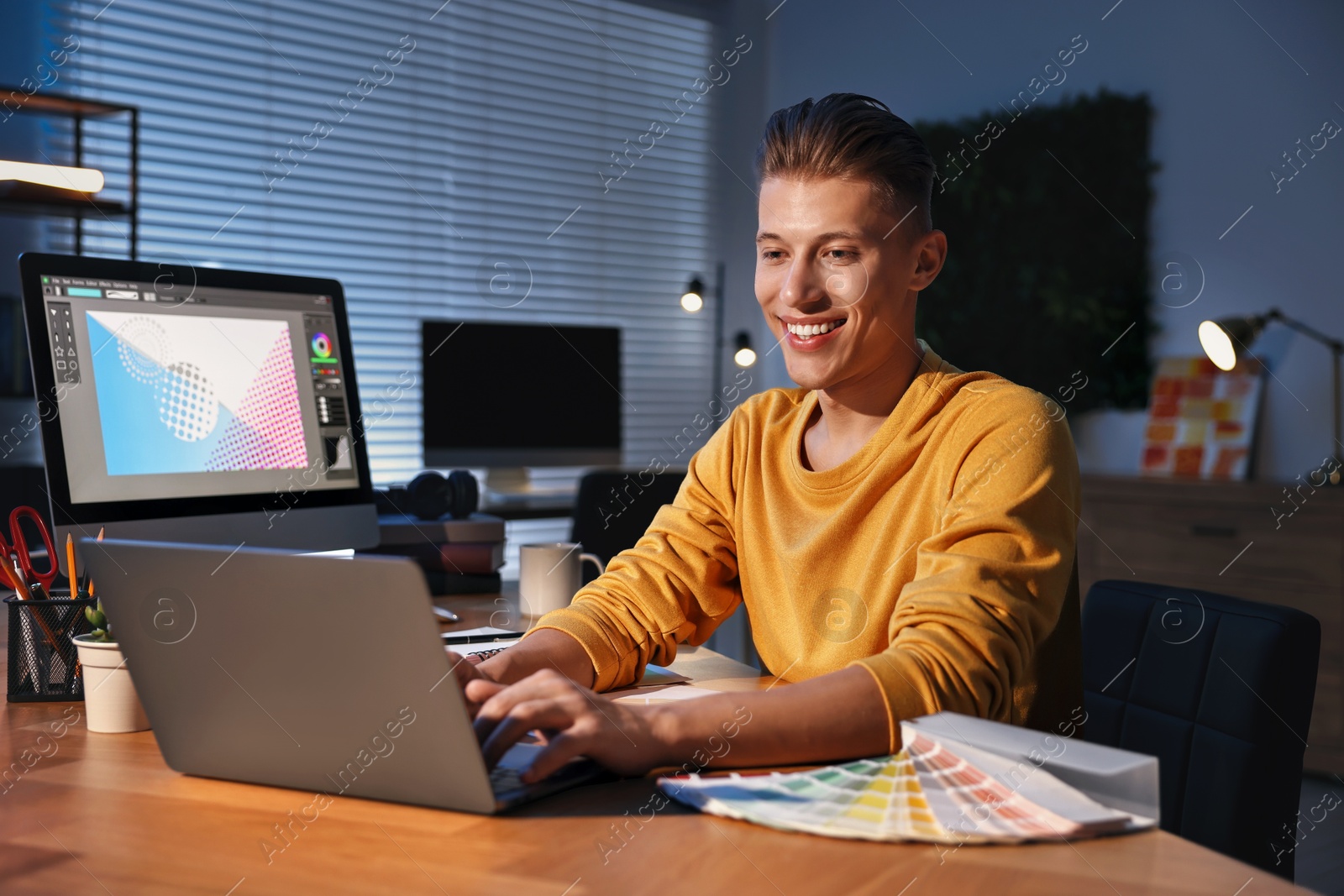 Photo of Designer working on laptop indoors at night