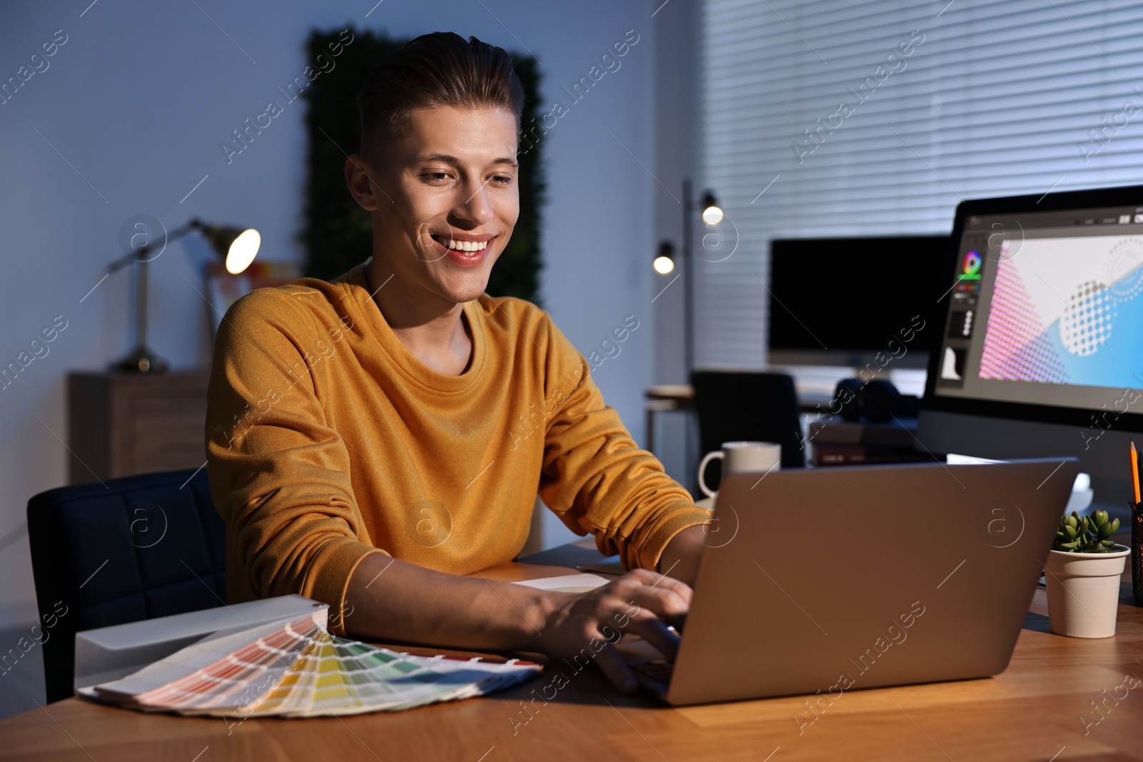 Photo of Designer working on laptop indoors at night