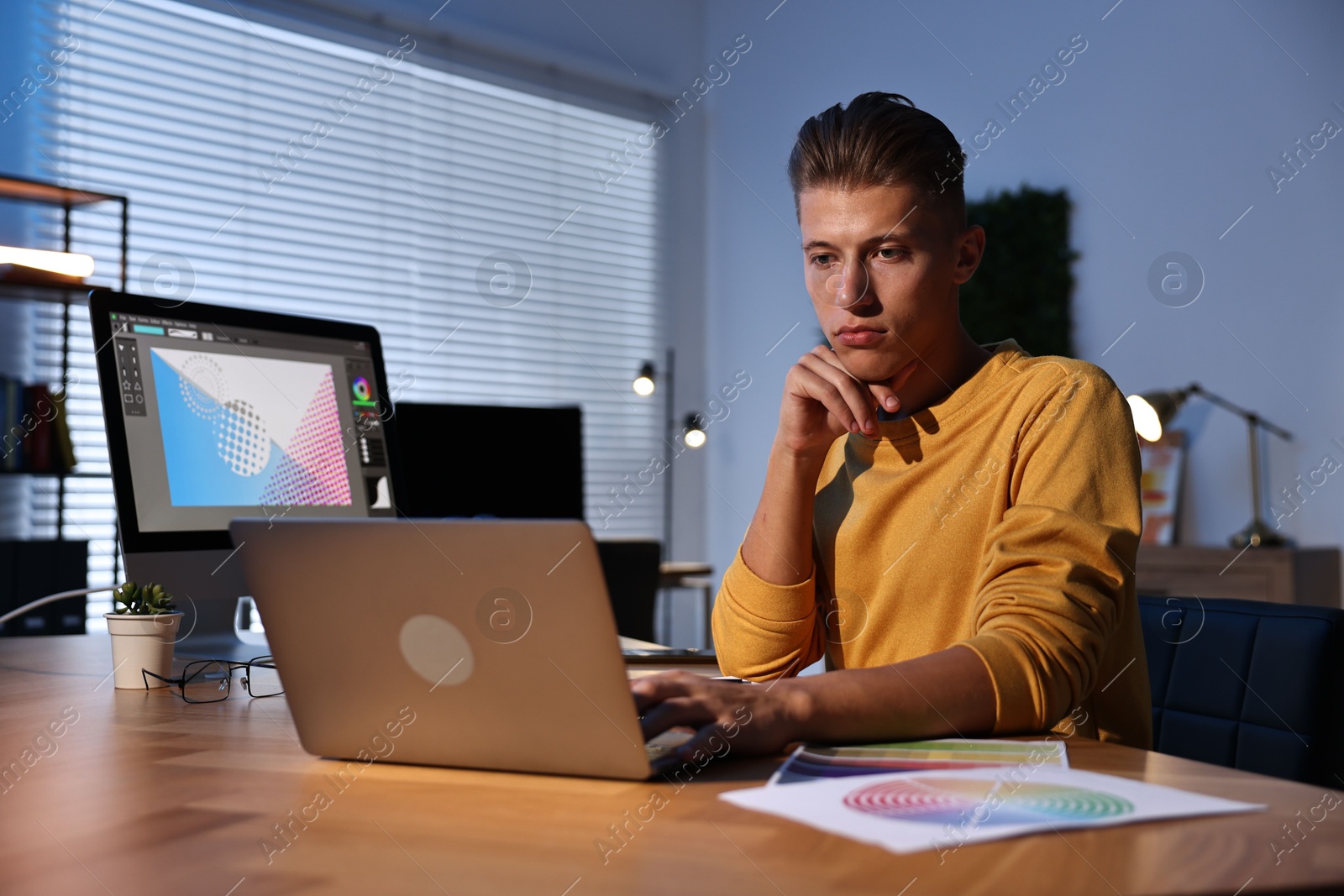 Photo of Designer working on laptop indoors at night