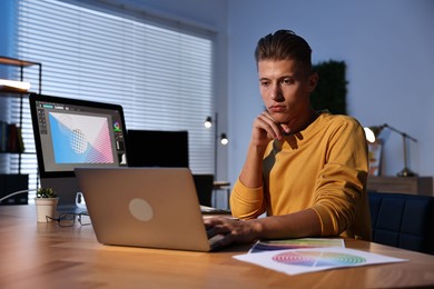 Photo of Designer working on laptop indoors at night