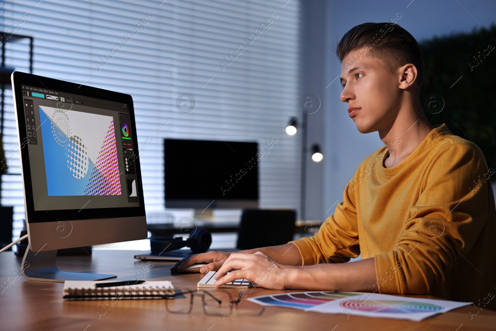 Photo of Designer working on computer indoors at night