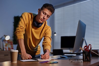 Photo of Designer taking notes in office at night