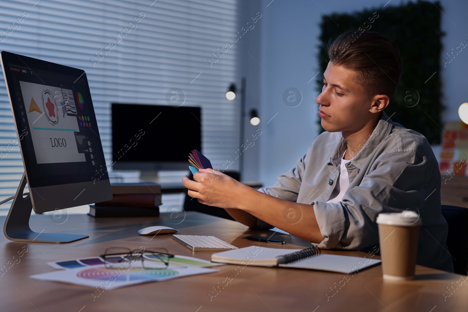 Photo of Designer with color sample cards working indoors at night