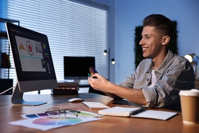 Photo of Designer with color sample cards working indoors at night