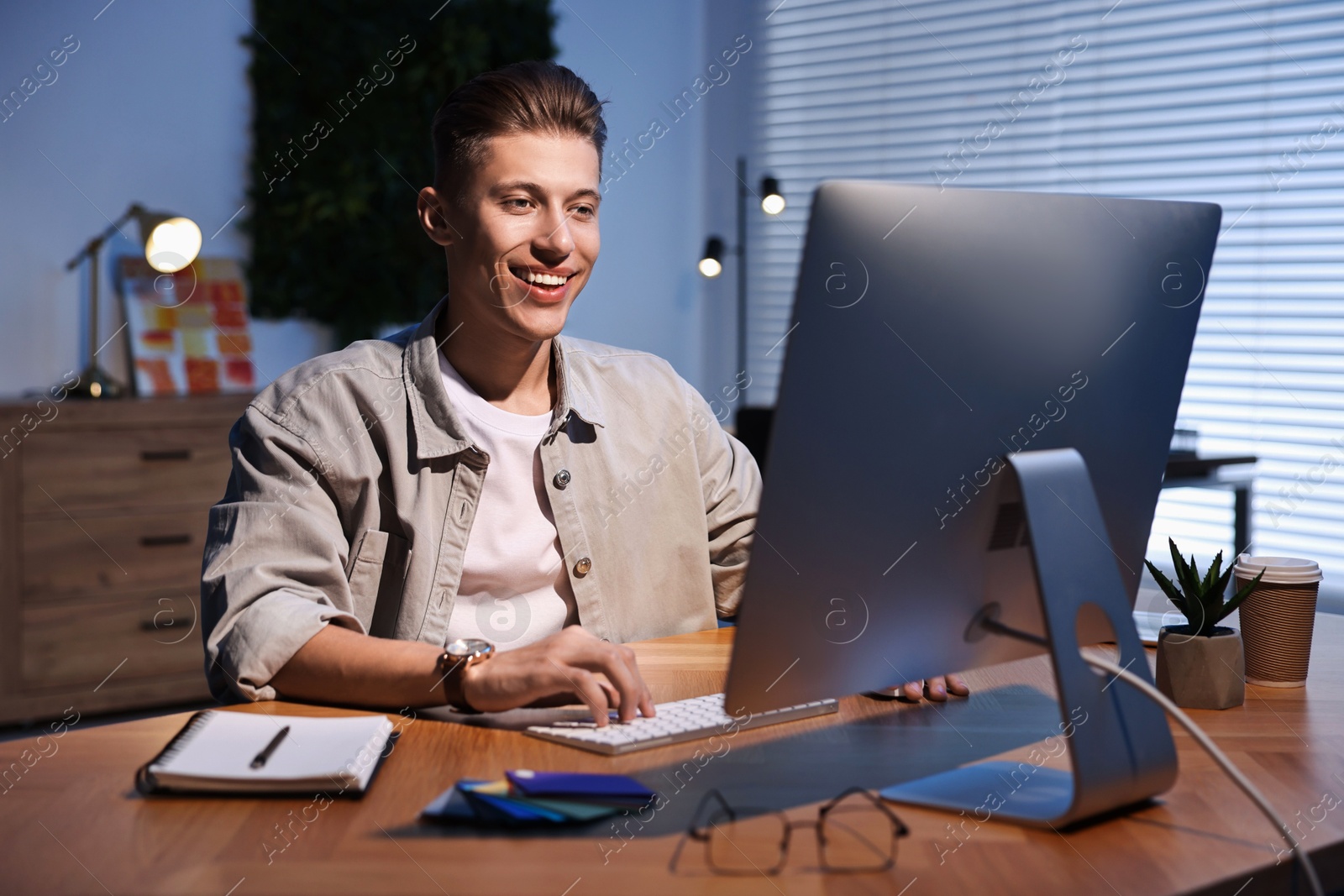 Photo of Designer working on computer indoors at night