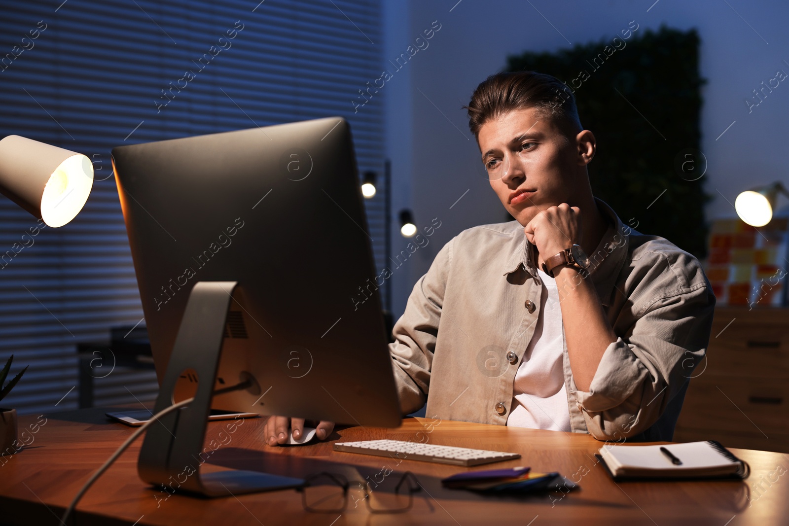 Photo of Designer working on computer indoors at night