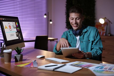 Photo of Designer with tablet working indoors at night