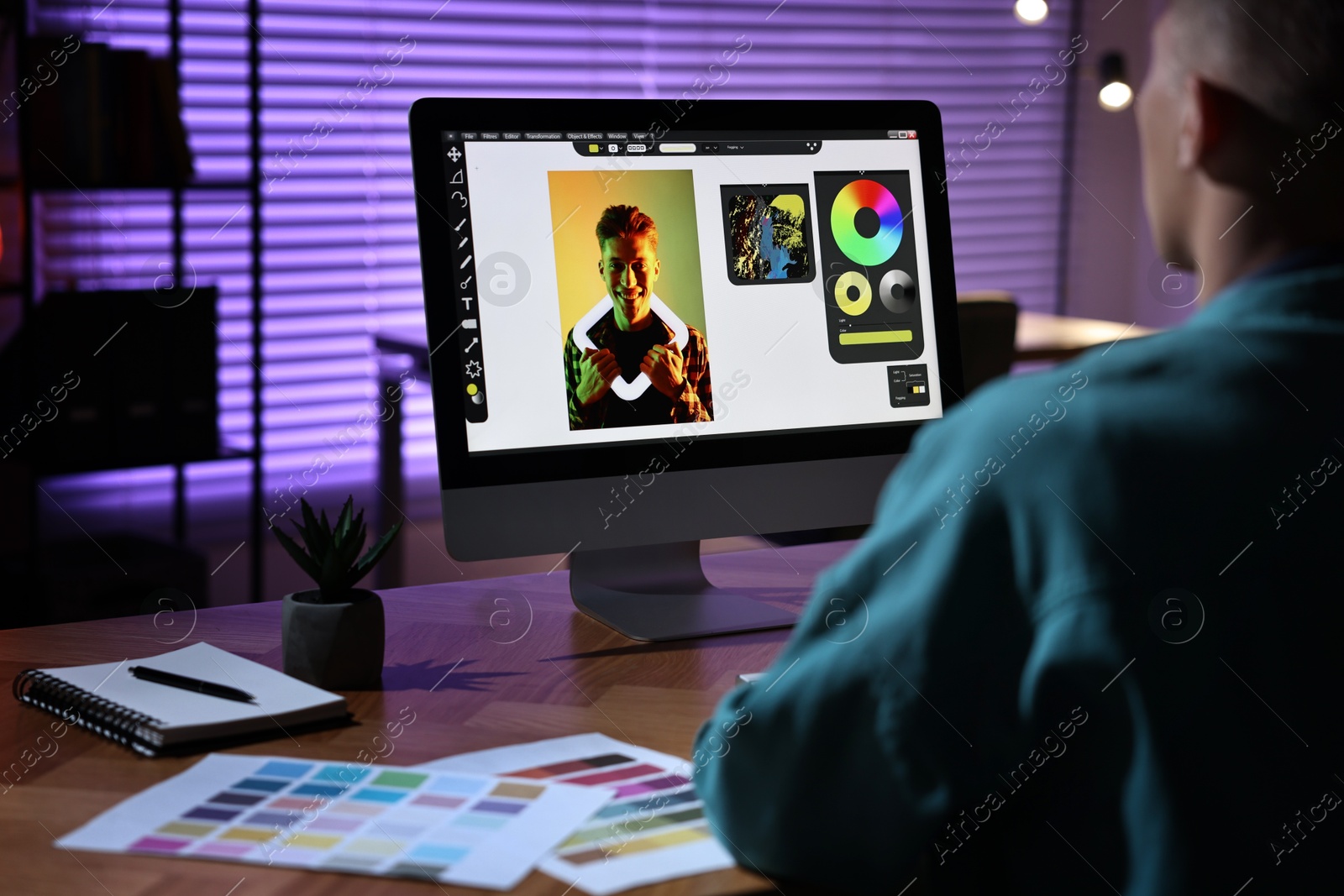 Photo of Designer working on computer indoors at night, closeup