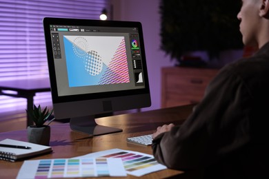 Photo of Designer working on computer indoors at night, closeup