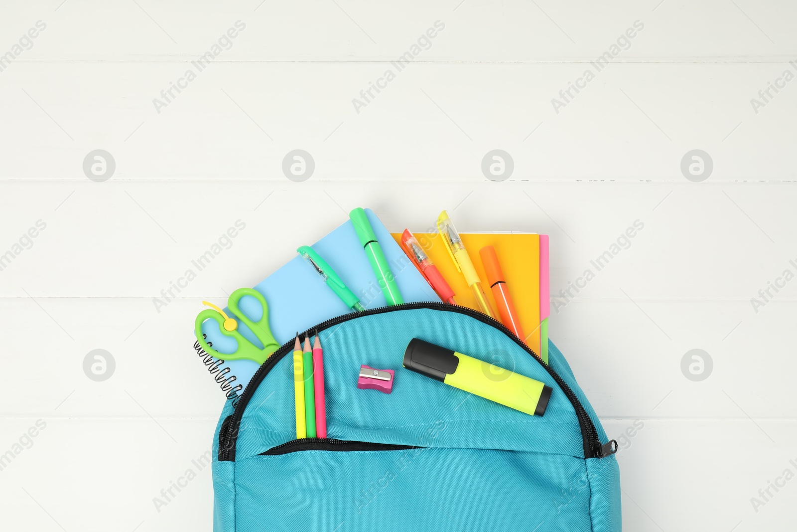 Photo of Backpack and different school supplies on white wooden background, top view. Space for text