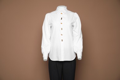 Female mannequin with stylish shirt and pants on light brown background