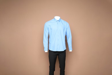 Photo of Male mannequin with stylish shirt and pants on light brown background