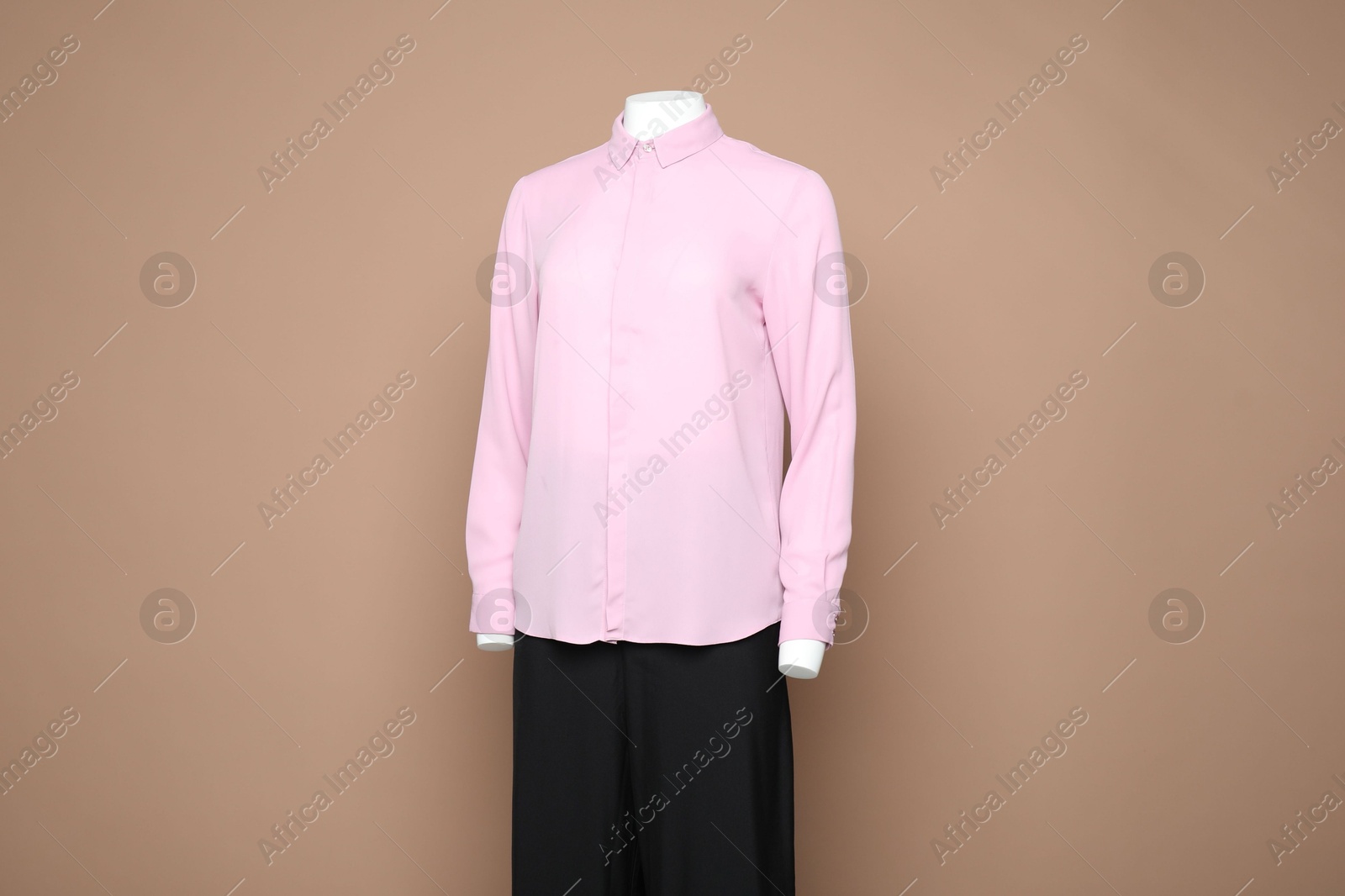 Photo of Female mannequin with stylish shirt and pants on light brown background