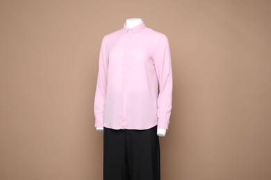 Photo of Female mannequin with stylish shirt and pants on light brown background