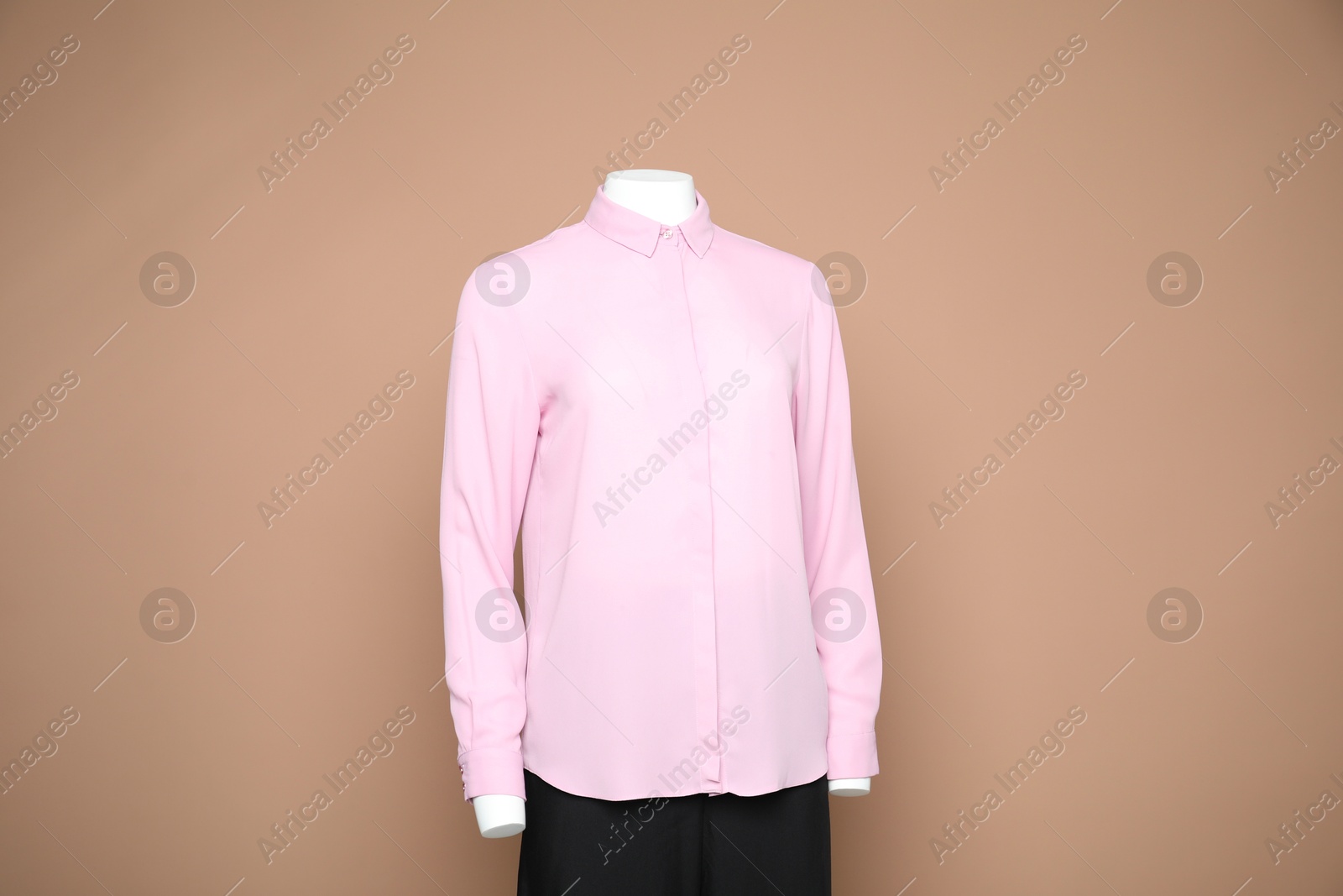 Photo of Female mannequin with stylish shirt and pants on light brown background