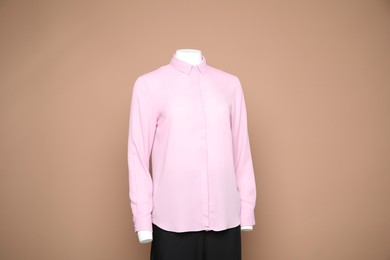 Photo of Female mannequin with stylish shirt and pants on light brown background