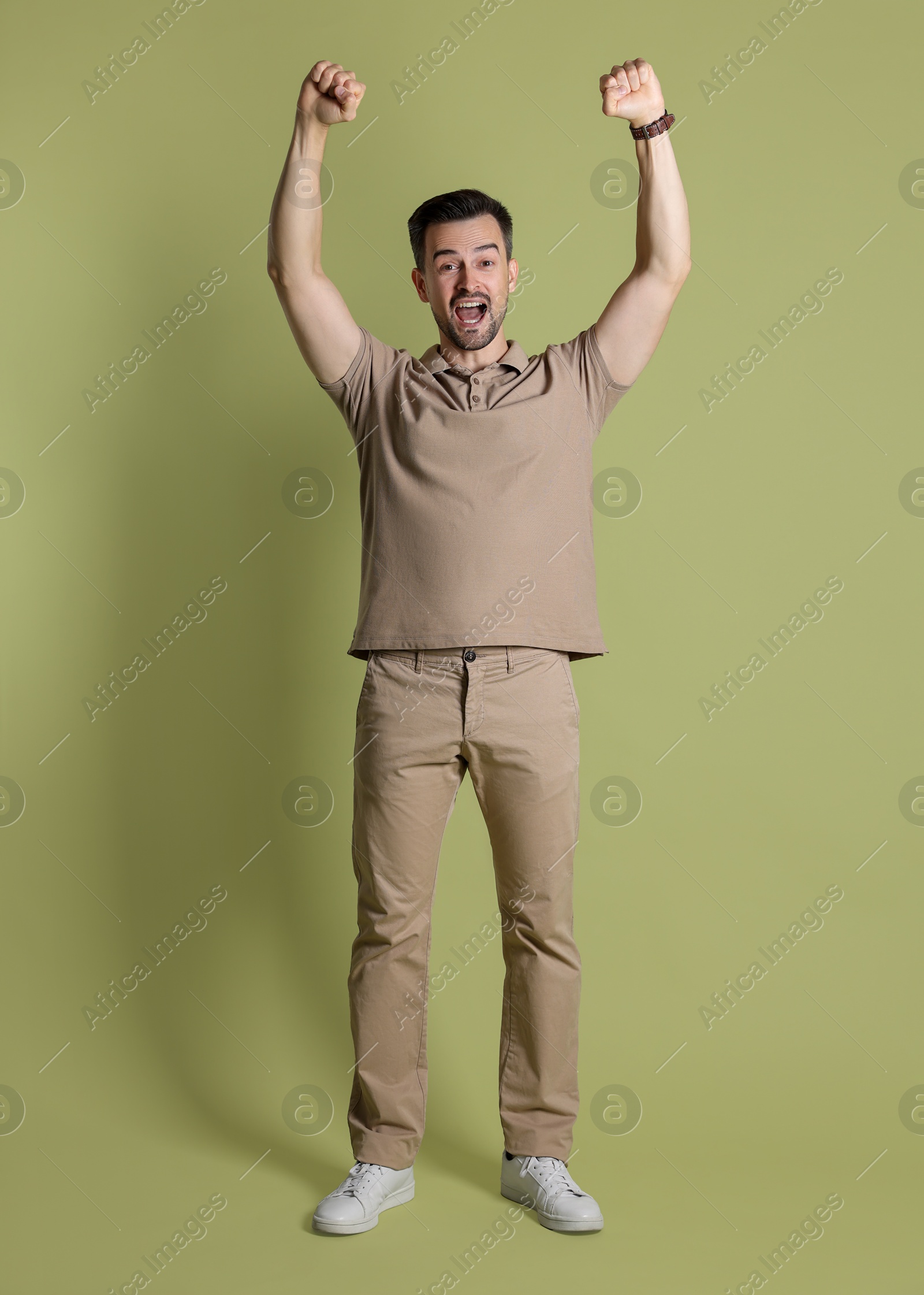 Photo of Portrait of happy winner on pale olive background