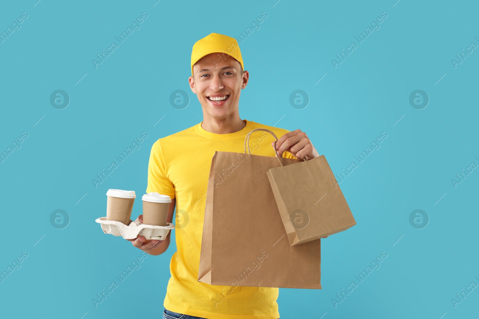 Photo of Fast-food worker with paper bags and cups on light blue background