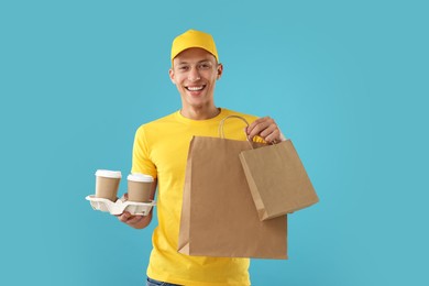 Photo of Fast-food worker with paper bags and cups on light blue background