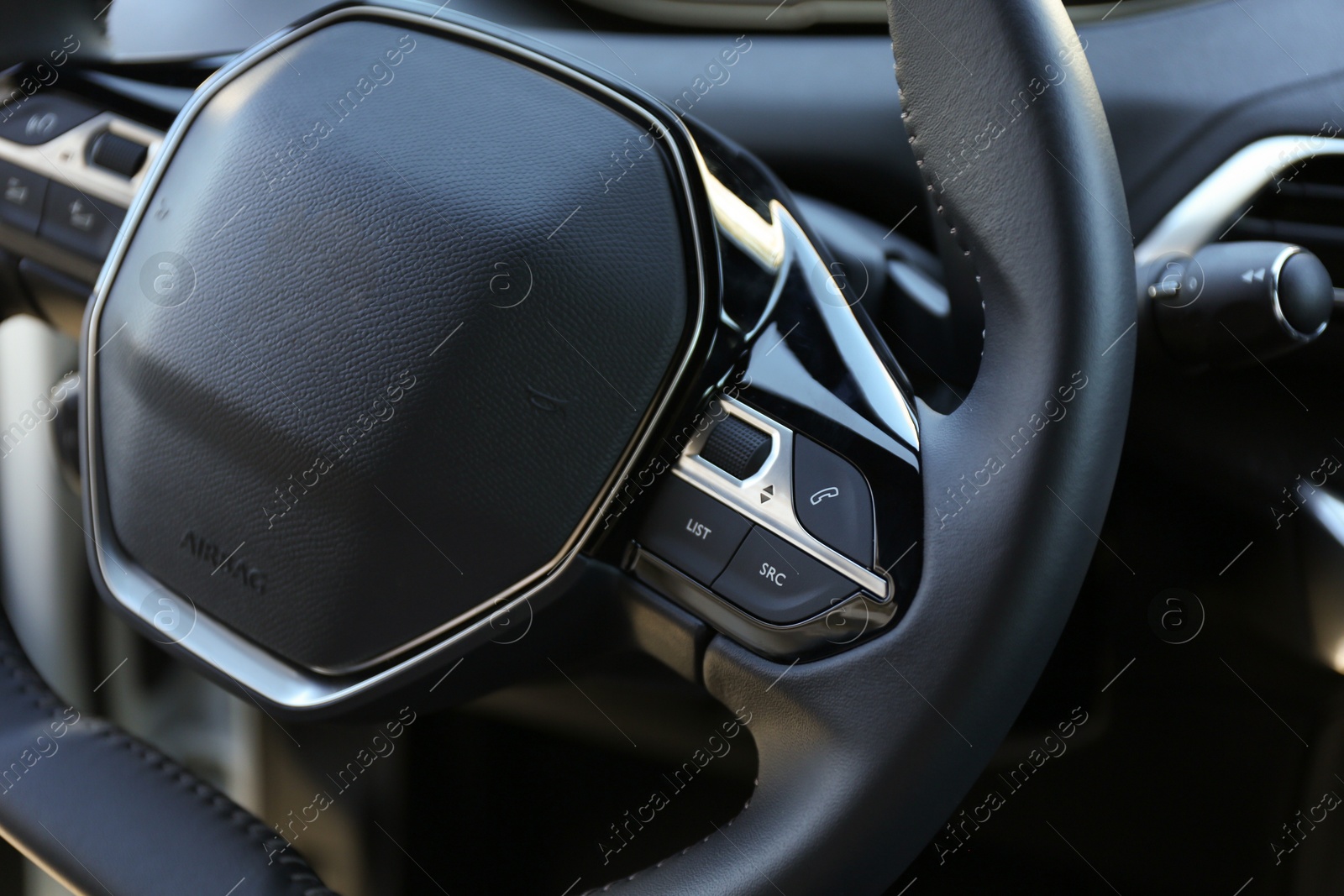 Photo of Steering wheel and dashboard inside of modern luxury car, closeup