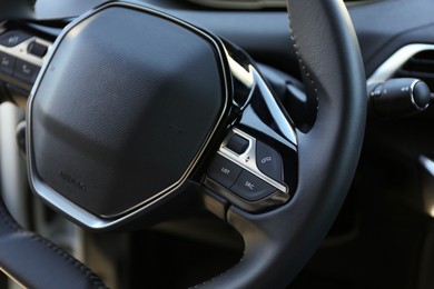 Photo of Steering wheel and dashboard inside of modern luxury car, closeup