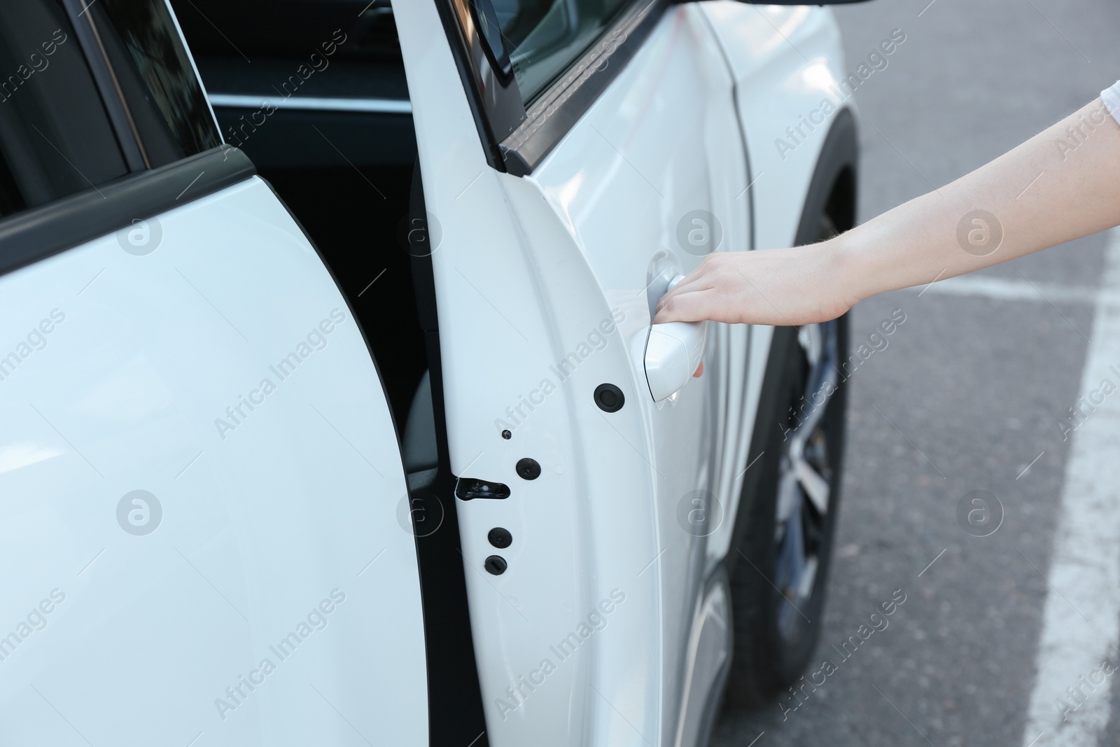 Photo of Woman opening door of white car outdoors, closeup