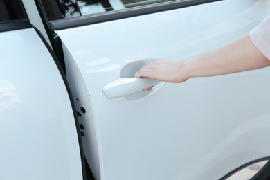 Photo of Woman opening door of white car outdoors, closeup