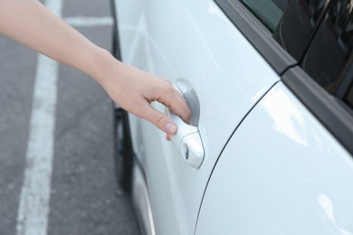 Photo of Woman opening door of white car outdoors, closeup