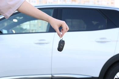 Photo of Woman holding key near car outdoors, closeup