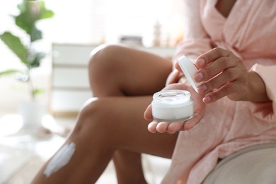 Woman with jar of cream at home, closeup