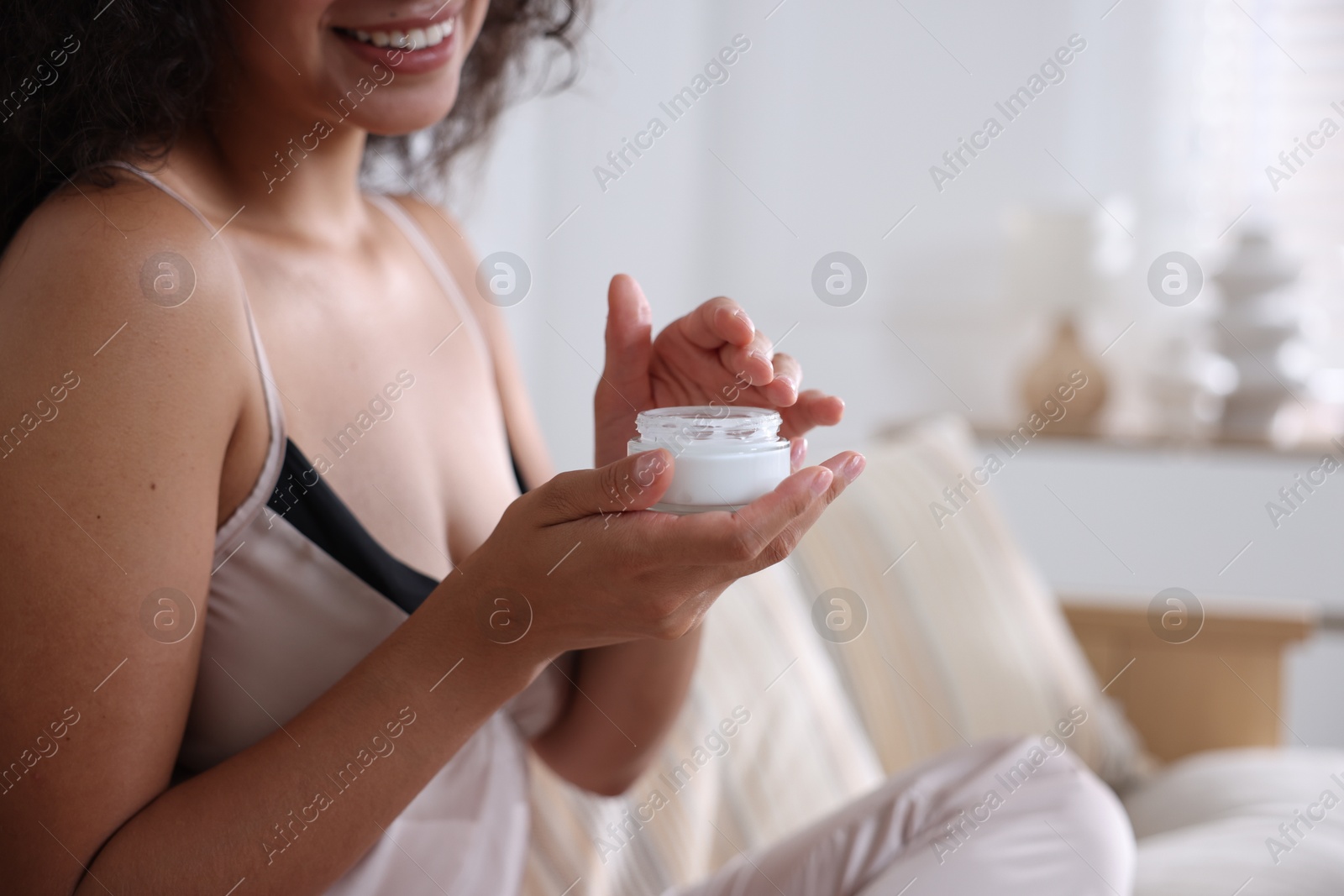 Photo of Woman with jar of cream on sofa at home, closeup. Space for text