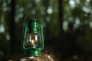 Photo of Vintage kerosene lamp in forest at evening, space for text