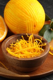 Photo of Fresh orange zest and fruit on black table