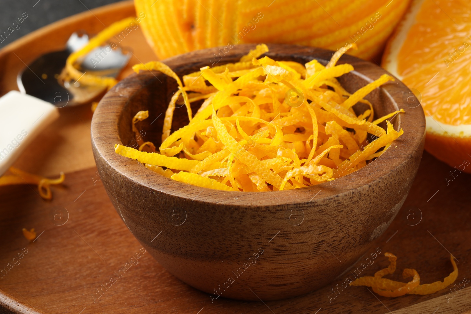 Photo of Fresh orange zest in wooden bowl, closeup