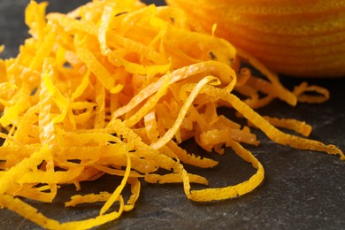 Fresh orange zest and fruit on black table, closeup