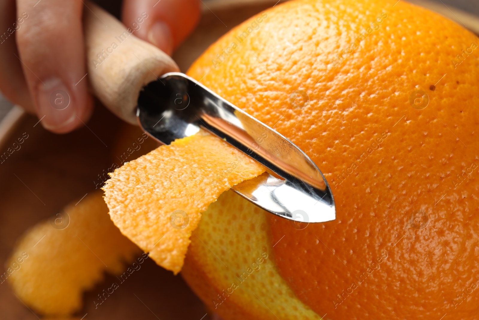 Photo of Woman zesting orange at wooden table, closeup