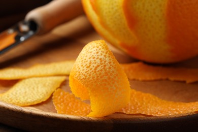 Photo of Fresh orange peel and fruit on wooden table, closeup