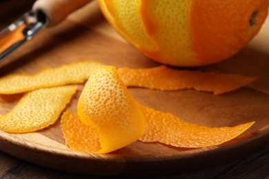 Photo of Fresh orange peel and fruit on wooden table, closeup