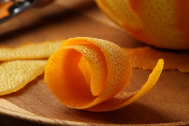 Photo of Fresh orange peel and fruit on wooden table, closeup