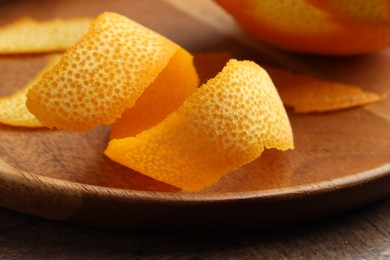 Photo of Fresh orange peel and fruit on wooden table, closeup